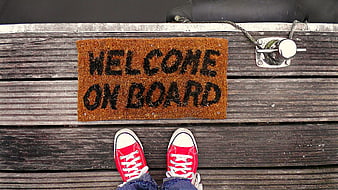 Red sneakers on wooden dock with welcome on board mat