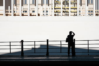 Silhouette of man standing by railing against white wall