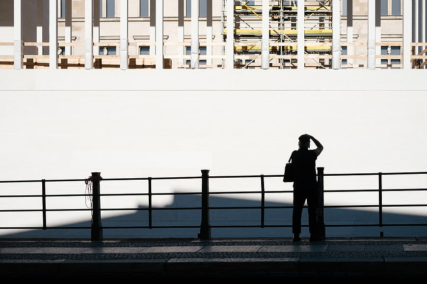 Silhouette of man standing by railing against white wall