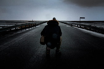 Person Kneeling on Wet Road in Winter Landscape