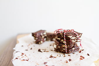 Stack of homemade chocolate almond bark tied with red and white baker's twine on parchment paper.
