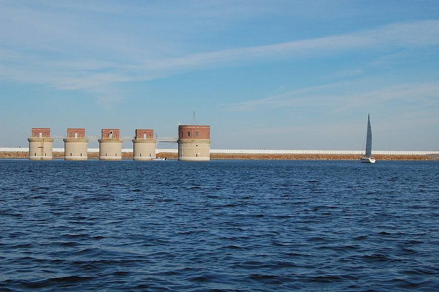 Sailboat passing historic brick fortifications on blue water