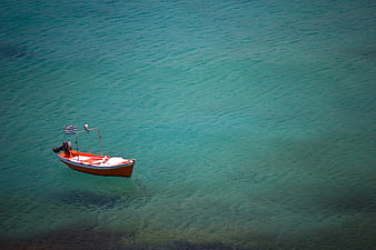 Aerial view of small orange boat in turquoise sea
