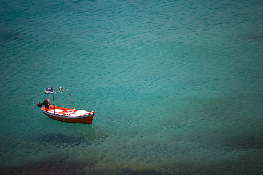 Aerial view of small orange boat in turquoise sea
