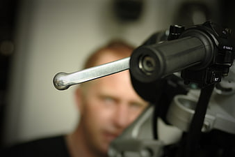 Close-up of motorcycle handlebar lever with blurred rider