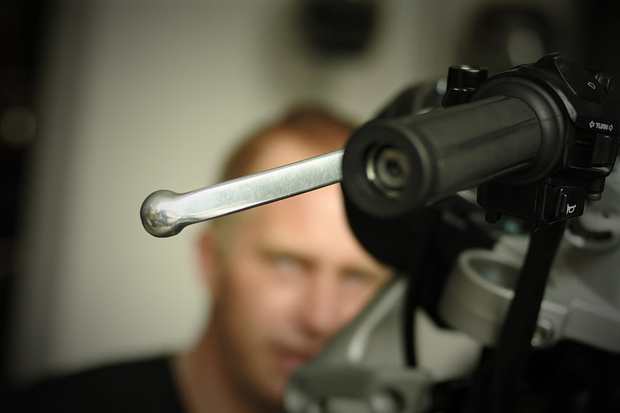 Close-up of motorcycle handlebar lever with blurred rider