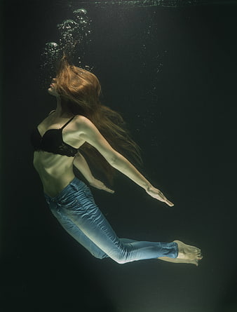 Underwater fashion portrait of a woman in jeans and black bra