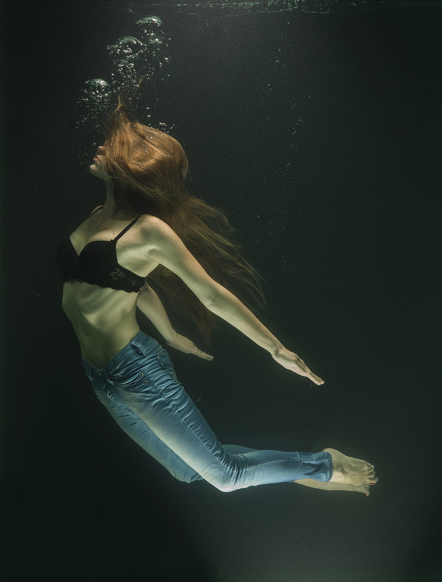 Underwater fashion portrait of a woman in jeans and black bra