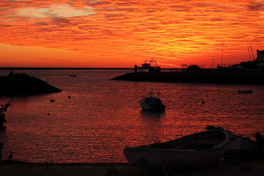 Dramatic orange sunset over harbor with silhouetted boats
