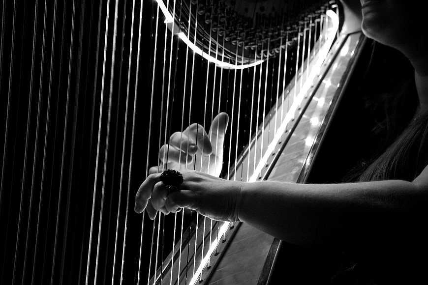 Black and white close-up of hands playing a concert harp