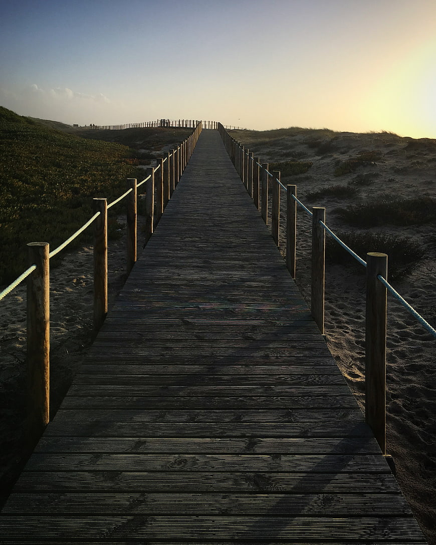 Wooden boardwalk path through sand dunes at sunset