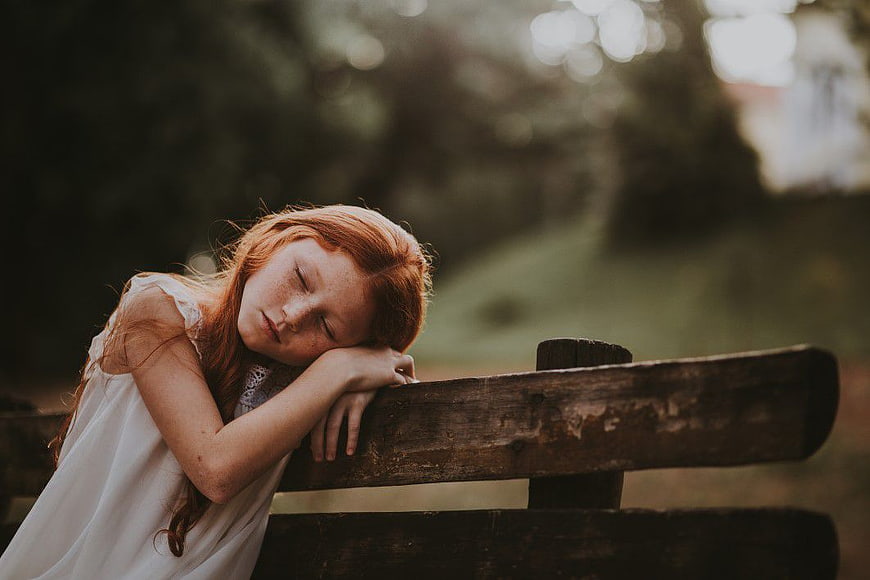 Sleeping Redhead Girl on Wooden Bench in Park