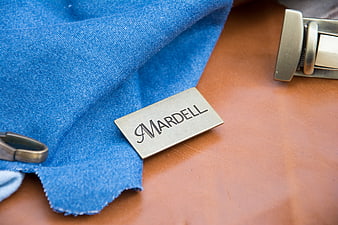 Mardell metal tag on blue denim and brown leather