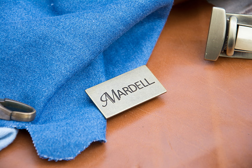 Mardell metal tag on blue denim and brown leather