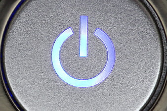 Close-up of glowing blue power button on silver laptop