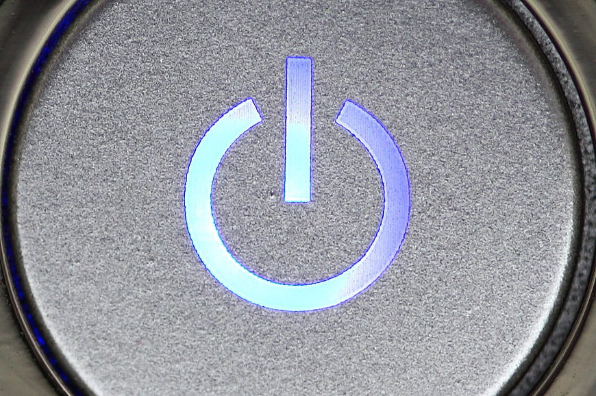 Close-up of glowing blue power button on silver laptop