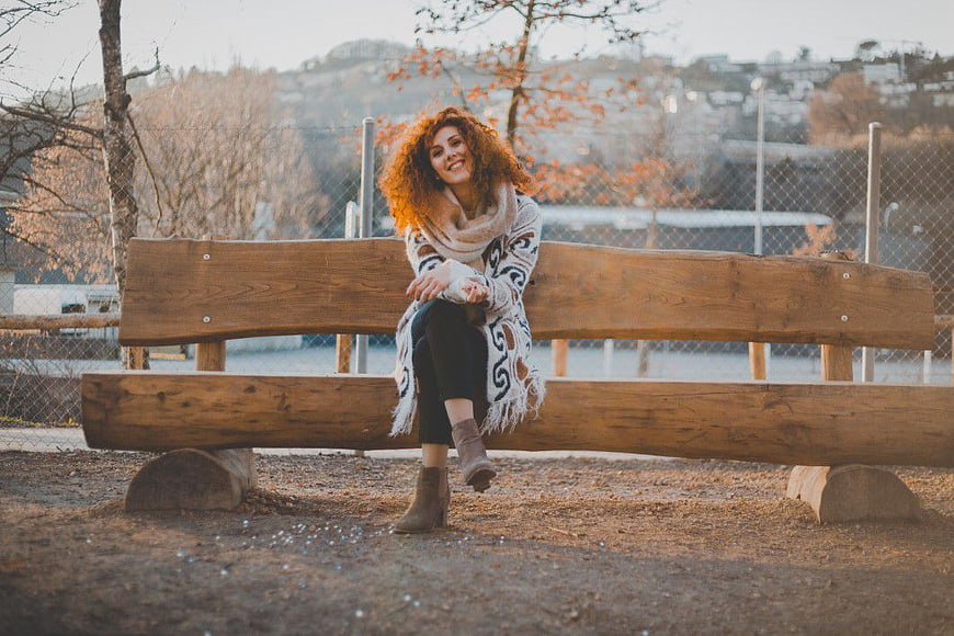 Smiling Redhead Woman Sitting on Wooden Park Bench