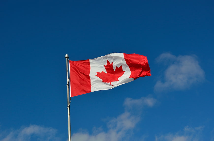Canadian flag waving against blue sky
