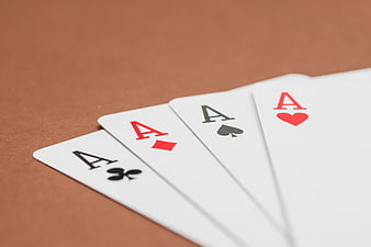 Four Aces Playing Cards Fanned on Brown Table