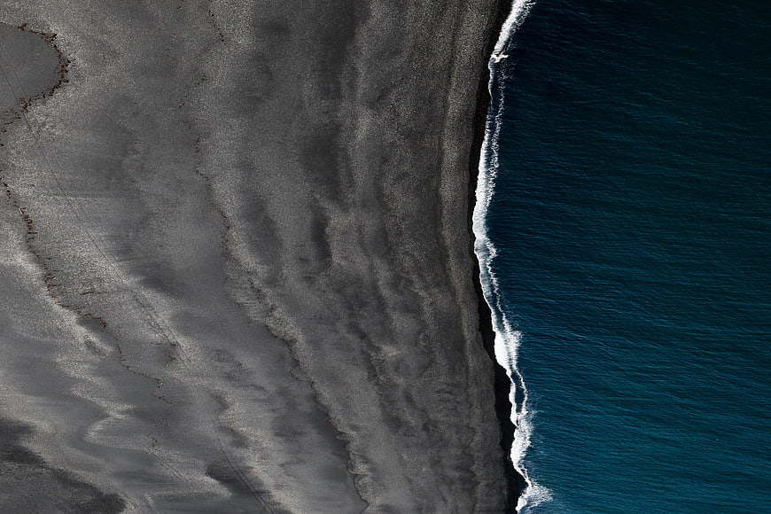 Aerial View of Dark Sand Beach and Blue Ocean Waves