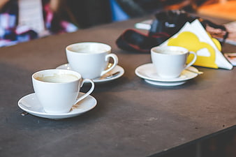 Three white coffee cups on a dark table