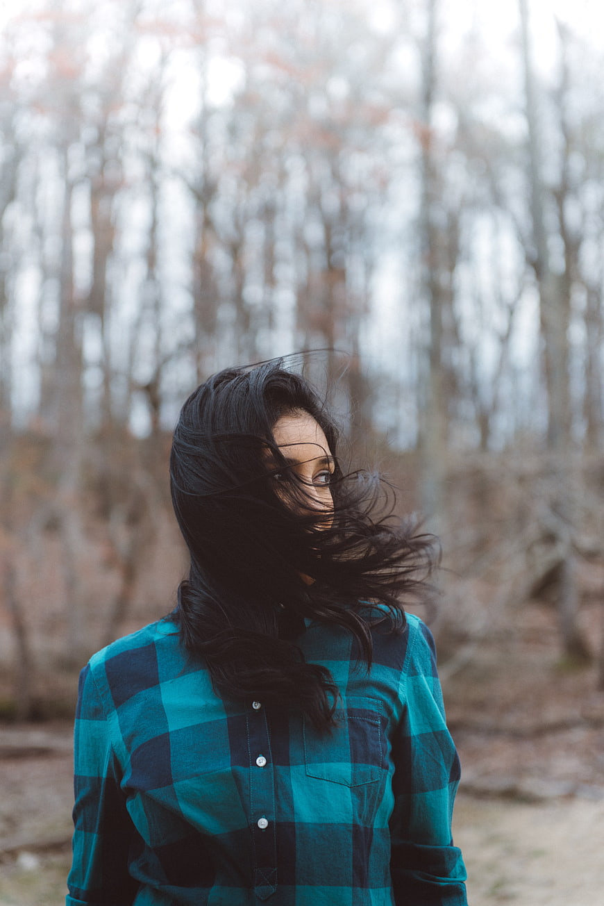 Woman in Plaid Shirt with Windblown Hair in Forest