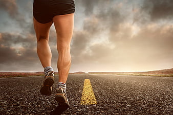 Runner legs on open road with dramatic sky