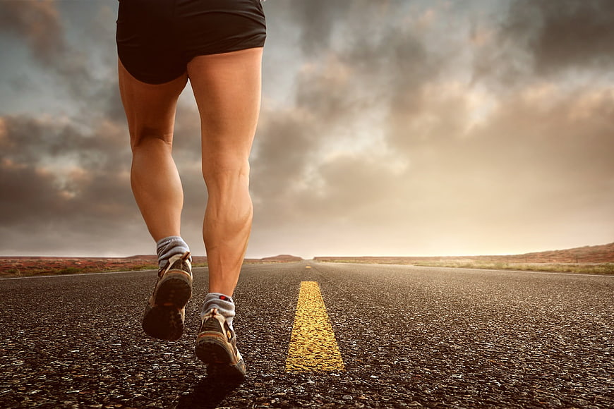 Runner legs on open road with dramatic sky