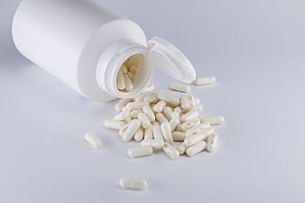 White Capsules Spilling From Open Plastic Bottle On Gray Background