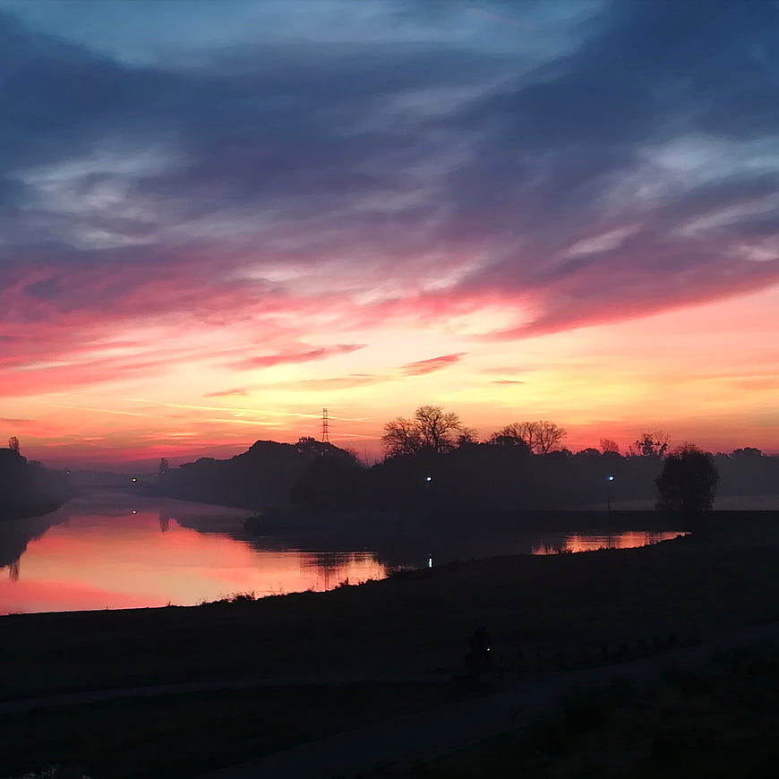 Vibrant pink and orange sunrise over a misty river landscape
