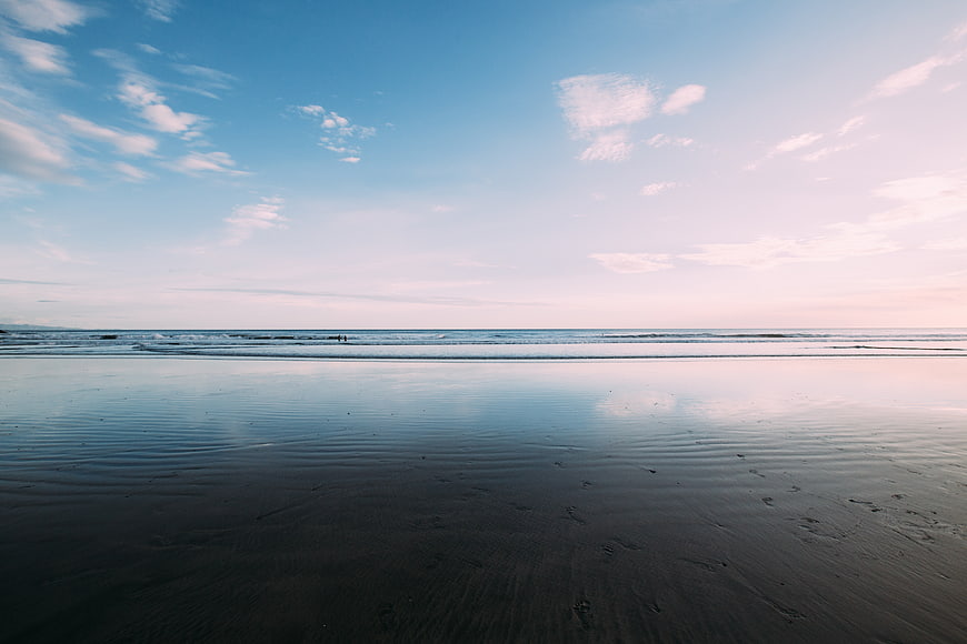 Serene Beach Landscape with Wet Sand Reflections and Blue Sky
