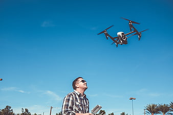 Man flying drone outdoors against blue sky