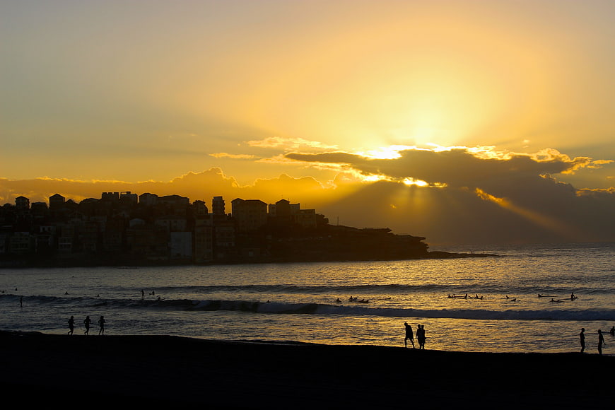 Silhouetted Beach Sunset with City Skyline and Surfers