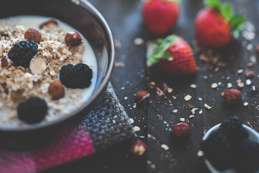 Healthy Oatmeal Bowl with Berries and Nuts on Dark Wood