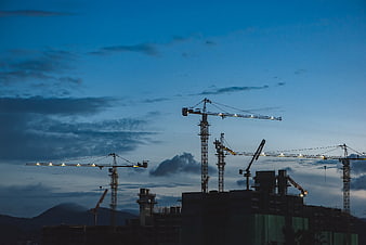 Construction Cranes Silhouette Against Blue Twilight Sky
