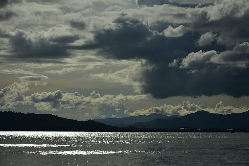 Dramatic Cloudy Sky Over Sparkling Sea and Silhouette Mountains