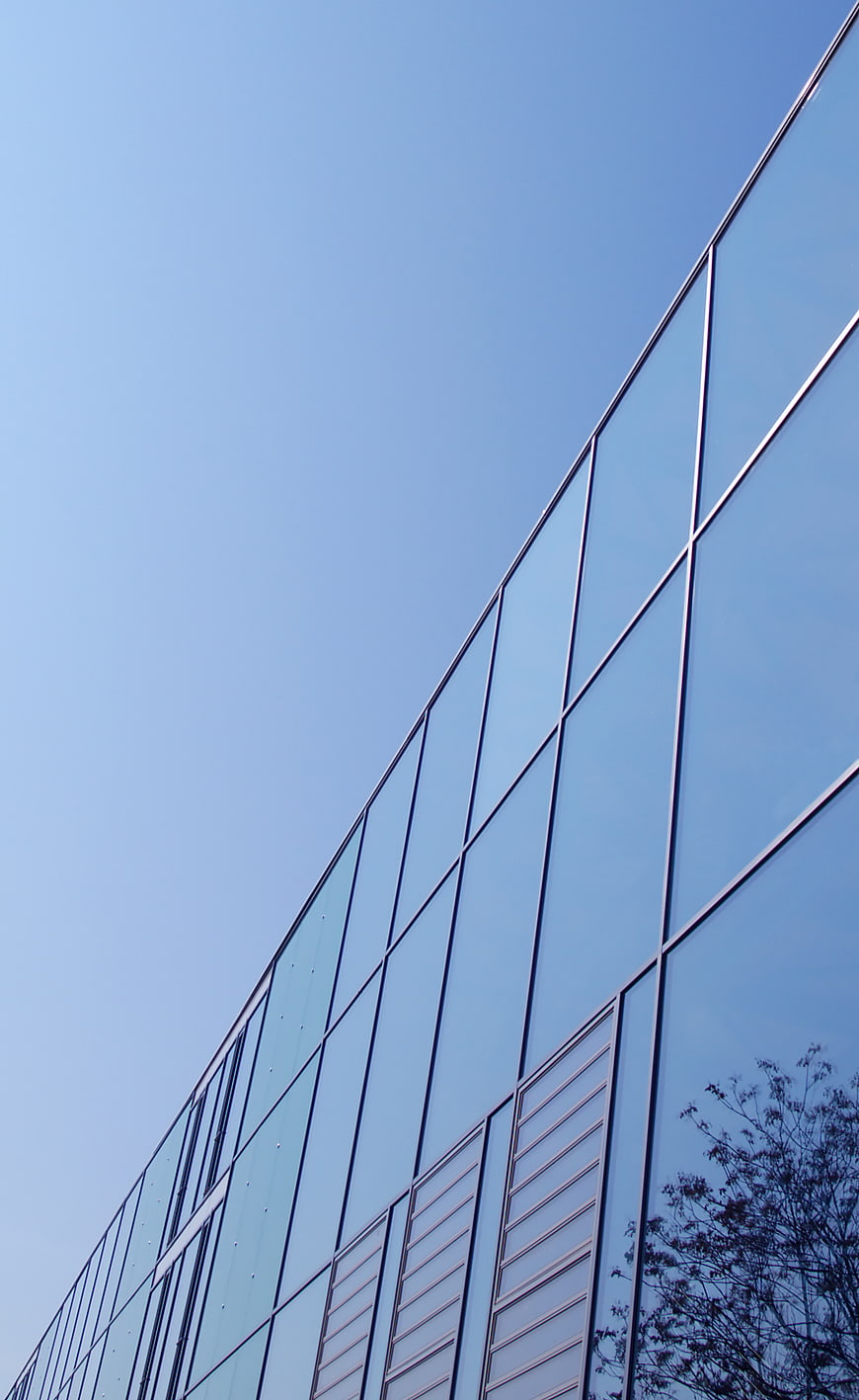 Modern Glass Office Building Facade Against Blue Sky