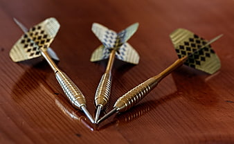 Three metal darts on wooden table