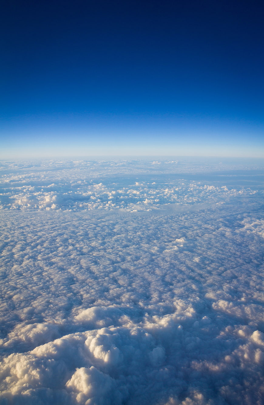 Aerial View of Fluffy Clouds Below Deep Blue Sky