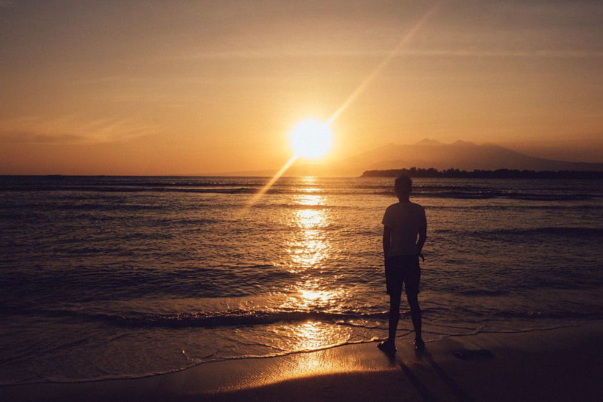 Silhouette of Man Watching Golden Sunset Over Ocean