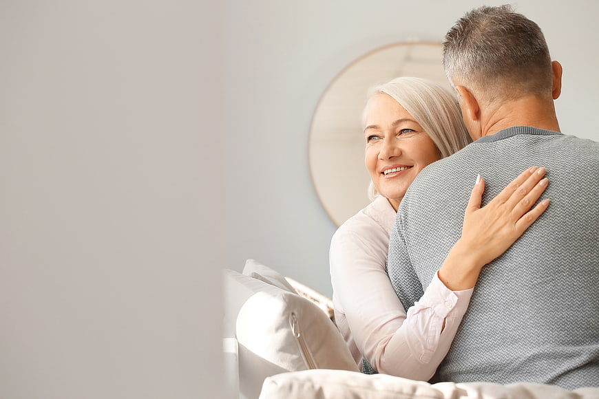Happy Senior Couple Embracing on Sofa with Copy Space