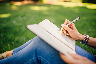 Woman Writing in Notebook on Grass Outdoors