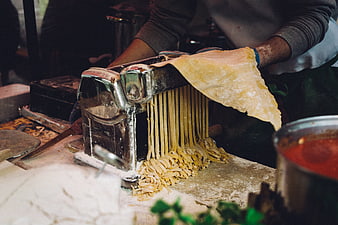 Homemade pasta being cut with a manual machine