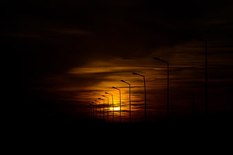 Silhouette of street lamps against dramatic orange sunset sky