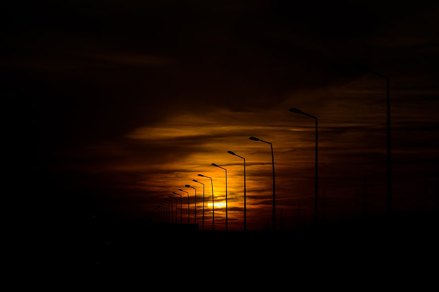 Silhouette of street lamps against dramatic orange sunset sky