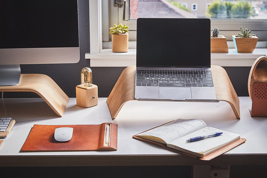 Minimalist wooden desk setup with laptop and notebook