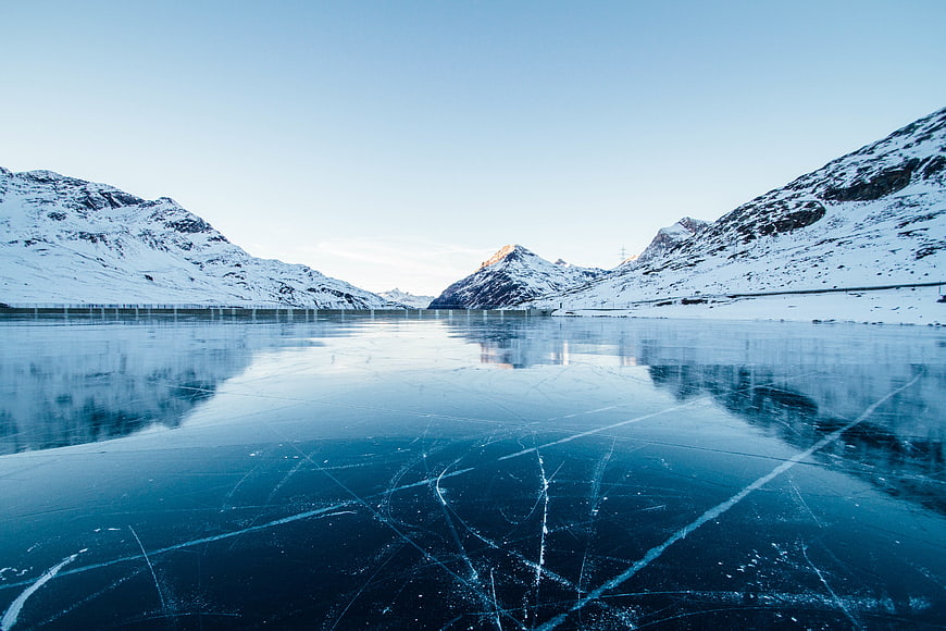 Frozen Lake with Cracked Ice and Snowy Mountains