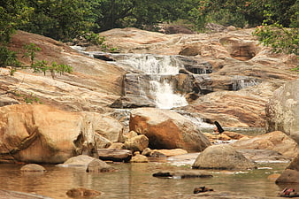 Natural waterfall cascading over smooth granite rocks in a forest