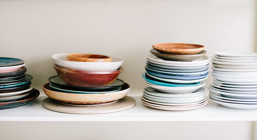 Stacks of colorful handmade ceramic plates and bowls on shelf