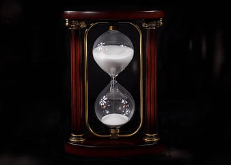 Vintage wooden hourglass with white sand on black background